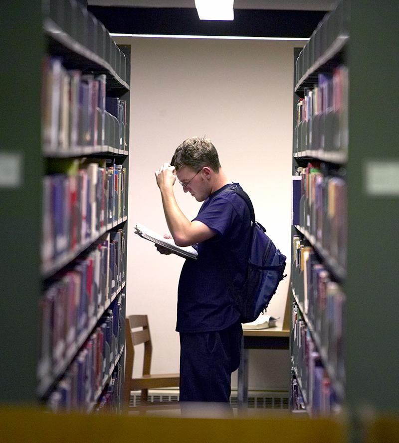 A student searches in the library stacks.